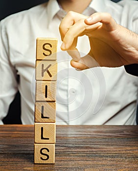 Businessman knocks down wooden blocks with the word Skills. The concept of the loss of skills. Suppression of talents. Business