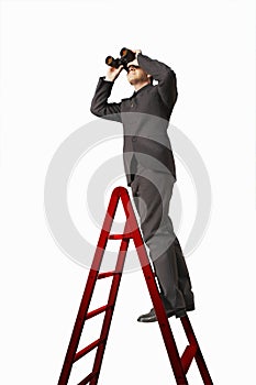 Businessman On Ladder Looking Through Binoculars