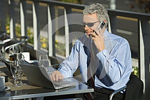 Businessman on laptop and cellphone.