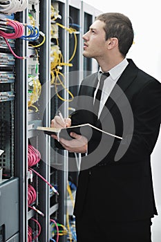 Businessman with laptop in network server room