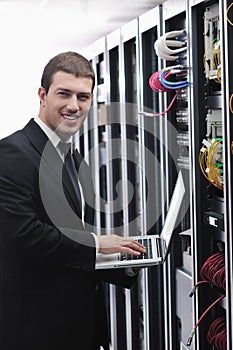 Businessman with laptop in network server room