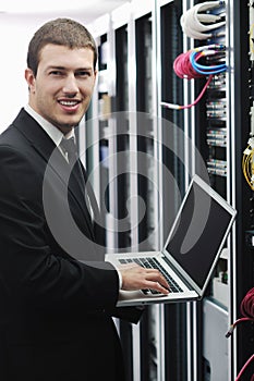 Businessman with laptop in network server room