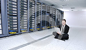 Businessman with laptop in network server room