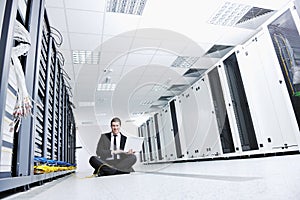 Businessman with laptop in network server room