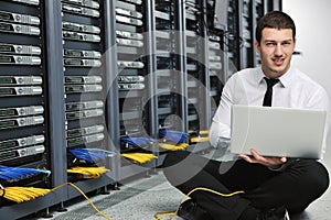 Businessman with laptop in network server room