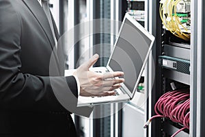 Businessman with laptop in network server room