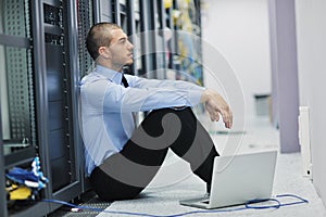 Businessman with laptop in network server room