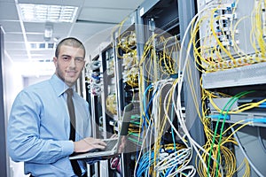 Businessman with laptop in network server room photo