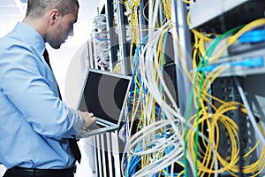 Businessman with laptop in network server room