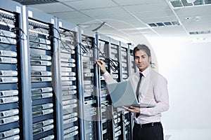 Businessman with laptop in network server room