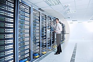 Businessman with laptop in network server room