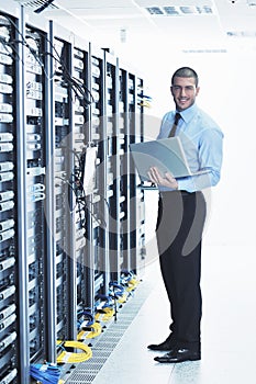 Businessman with laptop in network server room