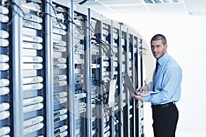 Businessman with laptop in network server room