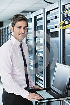 Businessman with laptop in network server room