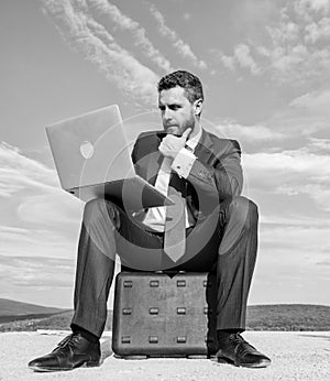 Businessman with laptop sit briefcase blue sky background. Laptop indispensable attribute modern businessman. Modern
