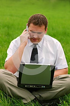 Businessman with laptop sitting in the grass