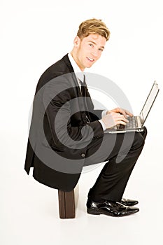 Businessman with laptop sitting on a suitcase