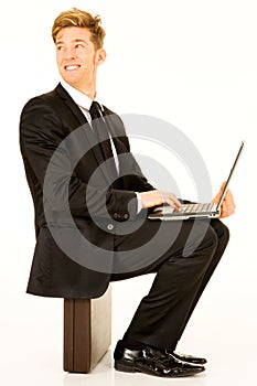 Businessman with laptop sitting on a suitcase