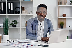 Businessman with laptop. Young African businessman is typing something on laptop in his office.