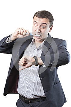 Businessman is late. Brushes his teeth and looks at his watch in panic.