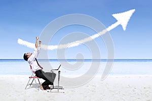 Businessman laughing in joy looking at success arrow sign at beach