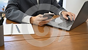 Businessman, lawyer or consultant working at his office desk, using smartphone and laptop