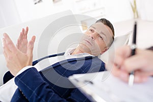 Businessman laying on couch talking to psychiatrist photo