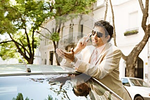 Businessman leaning on car.