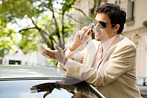 Businessman leaning on car.