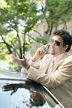 Businessman leaning on car.