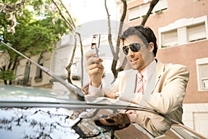 Businessman leaning on car.