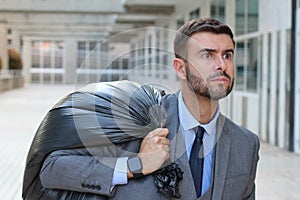 Businessman leaving office with full black plastic bag