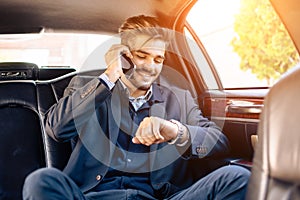 Businessman in limo, checking his watch