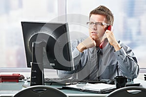 Businessman listening to landline call in office
