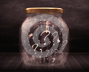 Businessman locked into a jar with question marks concept