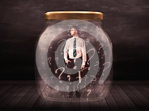 Businessman locked into a jar with question marks concept