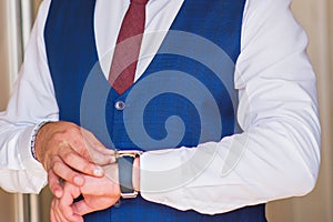 Businessman look his watch, a man in a blue suit and burgundy tie checks the time