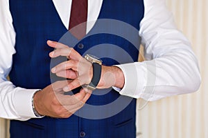 Businessman look his watch, a man in a blue suit and burgundy tie checks the time