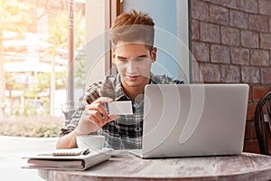 Businessman look at named card while using laptop on wooden tabl