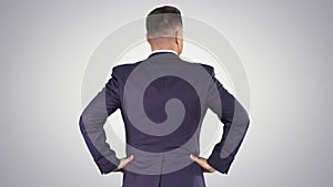 Businessman looking around with hands on hips on gradient background.