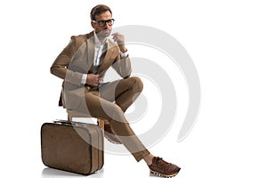 Businessman looking away, closing his jacket, sitting on a chair