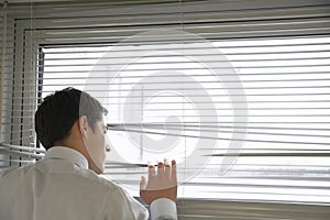 Businessman Looking Through Blinds