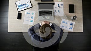 Businessman looking at bunch of money, income from lucrative business, top view