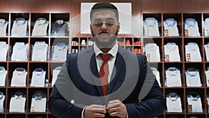 Businessman looking at the camera and choosing classical suit in the suit shop