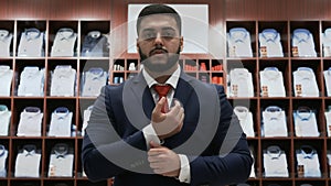 Businessman looking at the camera and choosing classical suit in the suit shop