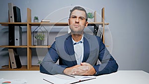 Businessman looking at camera near notebook and pen.