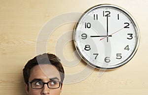 Businessman Looking At Clock On Wooden Wall In Office