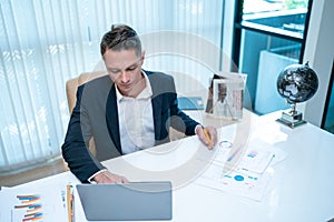 Businessman looking at a computer monitor during his working day in the office. Business and success concept
