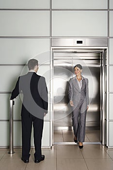 Businessman Looking At Female Colleague Exiting Elevator photo