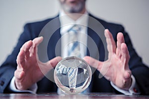 Businessman looking at glass ball on table